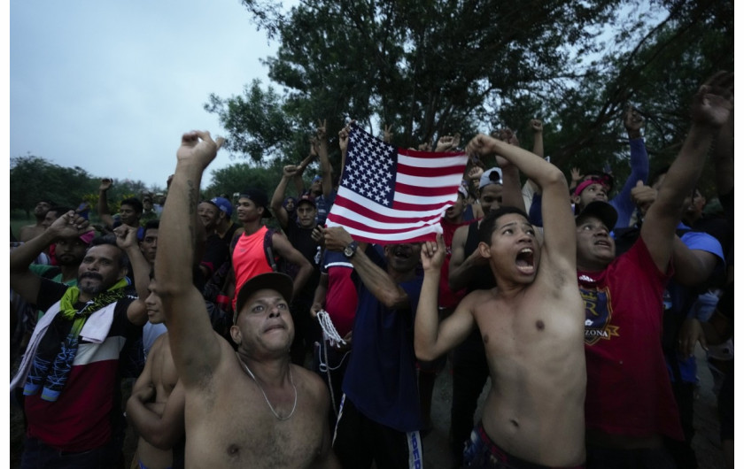 Wenezuelscy migranci machają flagą USA na widok helikoptera telewizyjnego, który przeleciał nad Rio Grande, w Matamoros w Meksyku, w piątek, 12 maja 2023 r., dzień po zniesieniu ograniczeń azylowych związanych z pandemią, zwanych Title 42. (AP Photo/Fernando Llano)