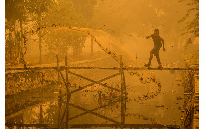 fot. Björn Vaughn (finalista), “Better a dirt fish than no fish at all!”, Za sprawą pożarów torfu w Indonezji, cały region Kalimantan pokrywa toksyczny smog. Mimo to wędkarz łowi ryby w skażonym kanale.