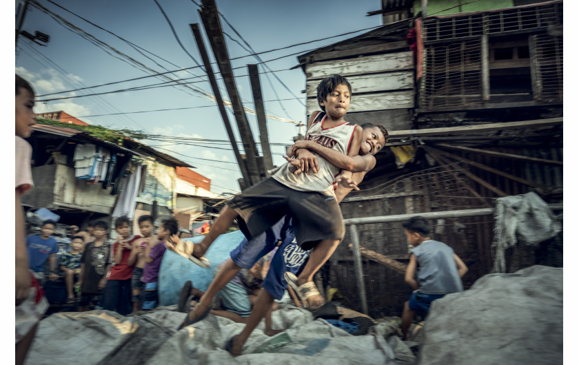 fot. Bernard Kwapiński, Happyland, Manila, FilipinyW 1995 roku władze Manili zamknęły przepełnione wysypisko śmieci, a pracujących tam ludzi przeniesiono na kawałek ziemi, który był składowiskiem odpadów żywności. Choć pozwolono zostać im jedynie na chwilę, nie opuścili tego miejsca i stworzyli jeden z największych slumsów, dający dzisiaj schronienie ponad 30. tysiącom mieszkańców. HAPPYLAND – ta oficjalna nazwa, powstała ze spontanicznie wymienionych liter w nazwie HAPILAN pochodzącej z lokalnego dialektu Visaian, a która w oryginale określała to miejsce jako ziemię cuchnącą. Historia jest zapisem zjawisk, które uznałem za najbardziej przejmujące, szczególnie tych, związanych z żyjącymi w tym nieszczęściu dziećmi.Bernard Kwapiński – fotograf z wykształcenia i zamiłowania. Absolwent Wydziału Fotografii Uniwersytetu w Dortmundzie (Visual Communication / Photography). Członek Press Club Polska oraz założyciel Fundacji Instytut Fotografii Fort, którą powołał w roku 2016 celem wspierania fotografii polskiej. Założyciel galerii fotograficznej działającej przy IFF, a także jedynej w Polsce, unikatowej czytelni fotograficznej na rzecz, której przekazał jedną z największych w kraju kolekcji książek fotograficznych. Publikował swoje prace w prasie zagranicznej i polskiej ( m.in. w National Geographic Polska) i prezentował swoje zdjęcia na portalach internetowych ( m.in. Lens Culture). Od trzech lat pracuje nad kilkoma długoterminowymi projektami, których celem będą publikacje książkowe.