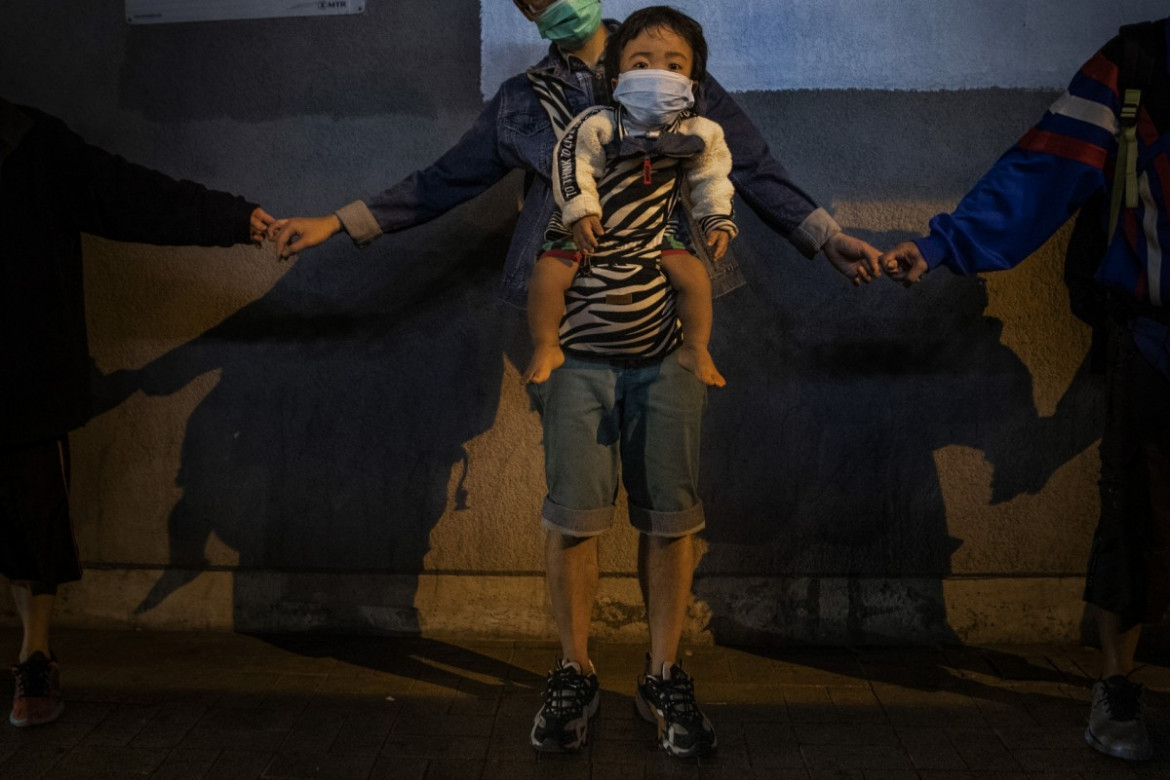 fot. Leah Millis. Dziecko w nosidełku sfotografowane podczas tworzenia "ludzkiego łańcucha" na rzecz solidarności z protestującymi w Kowloon Bay. Hong Kong, Chiny, 30 listopada 2019 /  Pulitzer Prize for Breaking News Photography 2020