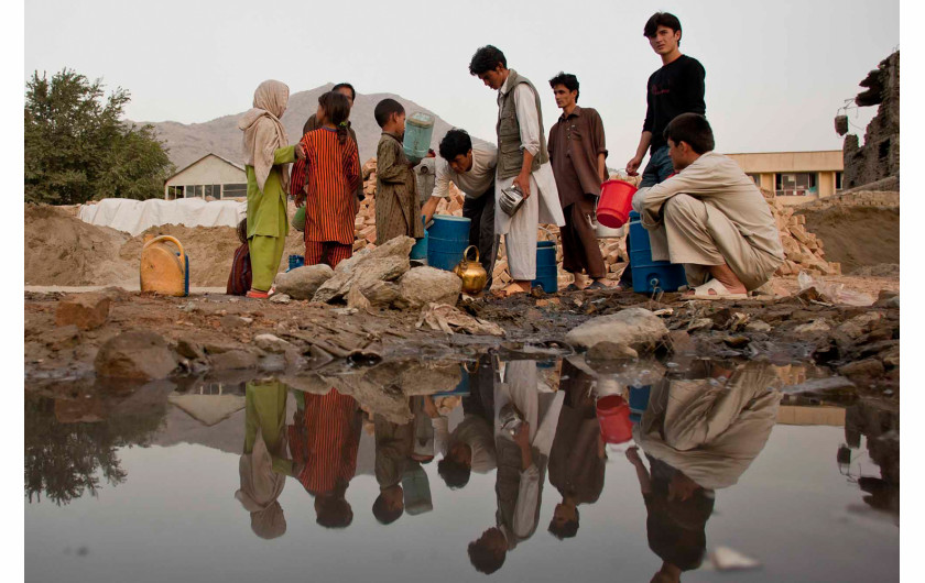 fot. Moe Zoyari | Odbicia Afgańczyków widoczne w wodzie, podczas gdy pompują wodę do swoich pojemników. Kabul, Afganistan.