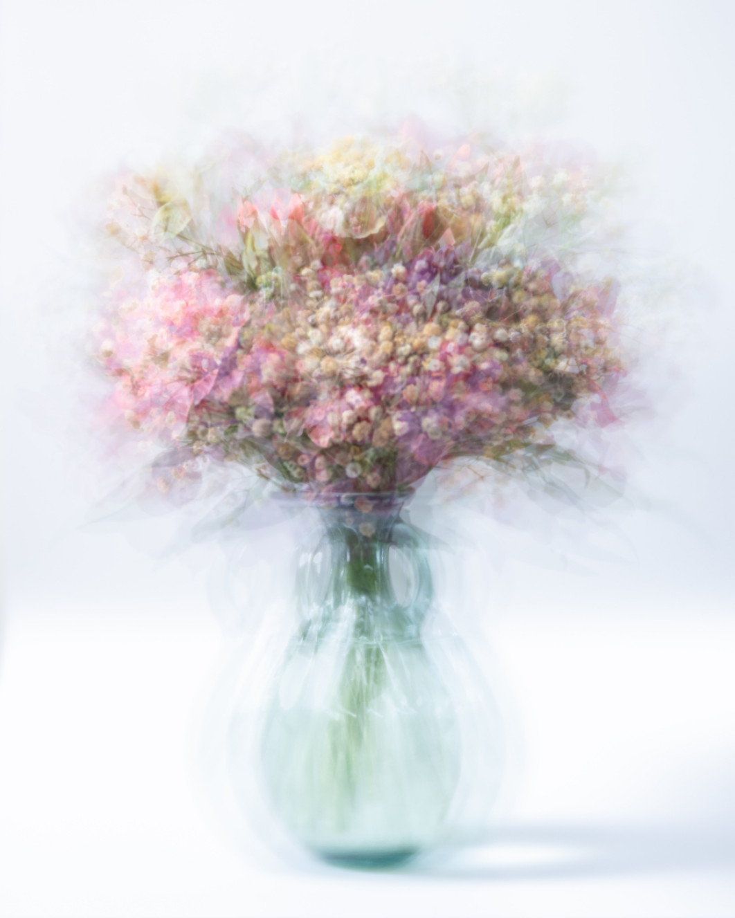 Fot. Ania Matczuk, "Still Life: Flowers in a glass vase", 3. miejsce w amatorskiej kategorii Experimental / Fine Art Photography Awards<br></br>Delikatny bukiet ujęty w minimalistycznym wazonie. Wykonana techniką wielokrotnej ekspozycji kompozycja pokazuje kwiaty w miękkich, półprzezroczystych warstwach, dzięki czemu formy odbijają się echem i subtelnie przenikają jedna w drugą. Efektem jest eteryczne studium kruchości i ruchu, w którym płatki zdają się zawieszone pomiędzy obecnością a zanikaniem. Obraz przekształca prosty układ kwiatów w kontemplacyjną medytację nad przemijaniem i pamięcią.