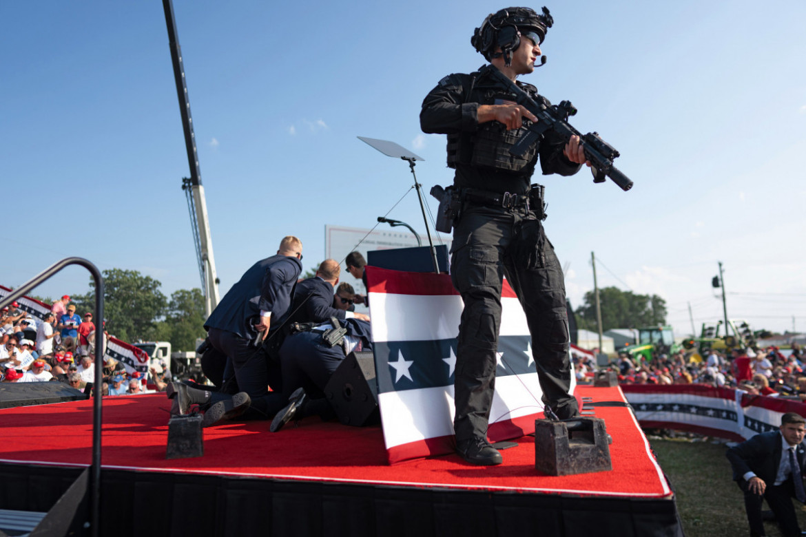 Fot. Doug Mills, The New York Times, Pulitzer Prize in Breaking News Photography 2025<br></br><br></br>Po tym, jak zamachowiec otworzył ogień, agenci z Secret Service Trumpa rzucili się, by go osłaniać i chronić przed kolejnymi strzałami. Członek zespołu antysnajperskiego Secret Service zajął miejsce na scenie, przeczesując teren w poszukiwaniu strzelca i innych potencjalnych zagrożeń.