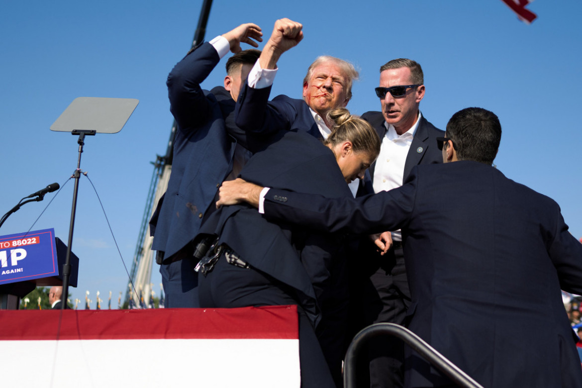 Fot. Doug Mills, The New York Times, Pulitzer Prize in Breaking News Photography 2025<br></br><br></br>Kiedy agenci zaczęli ewakuować rannego Trumpa ze sceny w bezpieczne miejsce, ten na chwilę ich zatrzymał i zaczął gestykulować do tłumu zwolenników. Podnosząc pięść, wyzywająco krzyknął: "Walczie! Walczcie! Walczcie!" Było to działanie instynktowne, które później zostało wykorzystane w kampanii wyborczej.