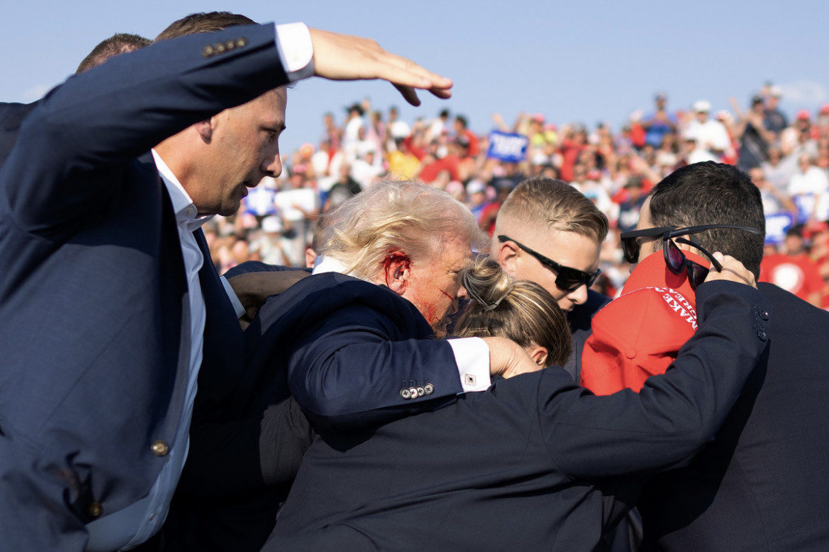 Fot. Doug Mills, The New York Times, Pulitzer Prize in Breaking News Photography 2025<br></br><br></br>Na zdjęciu widać zakrwawione ucho Trumpa, gdy agenci odsuwają go od miejsca zdarzenia. Jeden z agentów wyciąga rękę nad głowę, aby zmniejszyć widoczność byłego prezydenta na wypadek, gdyby padło więcej strzałów.
