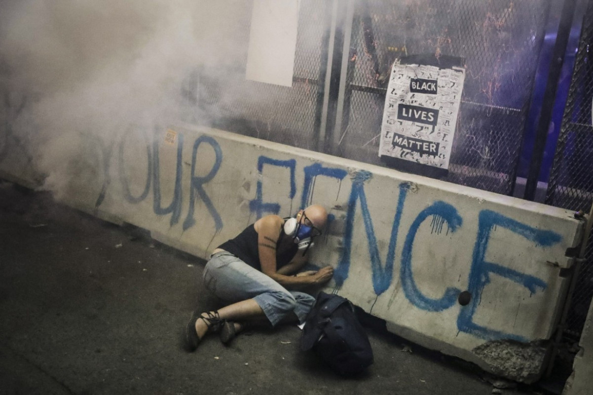 Jeden z protestujących ukrywa się za betonową barierą, podczas gdy funkcjonariusze uwalniają gaz łzawiący. Demonstracja Black Lives Matter w sądzie USA im. Marka O. Hatfielda, 29 lipca 2020 r. w Portland w stanie Oregon (Zdjęcie: Marcio Jose Sanchez.) / Pulitzer Prize 2021 for Breaking News Photography