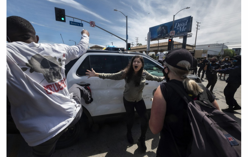 Protestująca ( w centrum) próbuje powstrzymać innych przed atakiem na radiowóz podczas protestu w sprawie śmierci George'a Floyda w Los Angeles, 30 maja 2020 r. (Zdjęcie: Ringo H.W. Chiu.) / Pulitzer Prize 2021 for Breaking News Photography