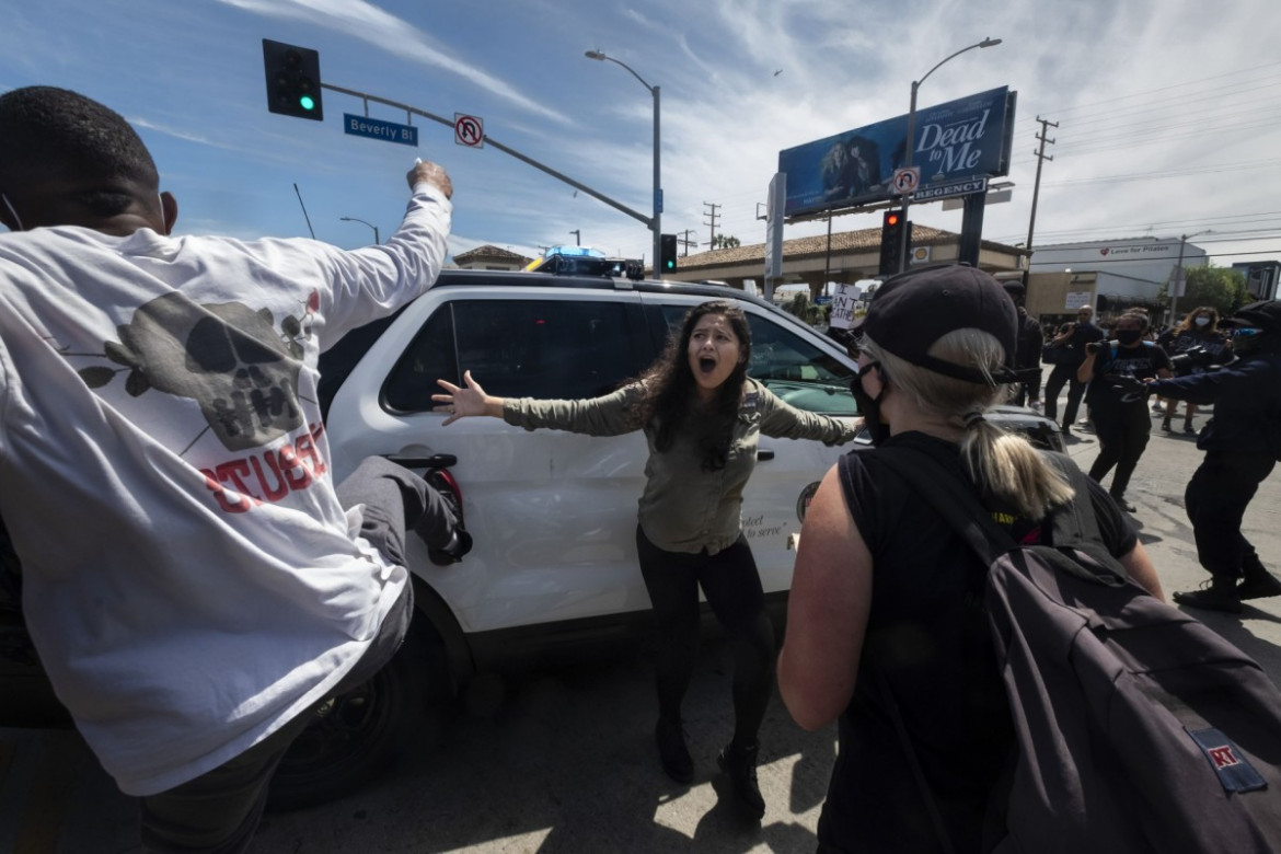 Protestująca ( w centrum) próbuje powstrzymać innych przed atakiem na radiowóz podczas protestu w sprawie śmierci George'a Floyda w Los Angeles, 30 maja 2020 r. (Zdjęcie: Ringo H.W. Chiu.) / Pulitzer Prize 2021 for Breaking News Photography