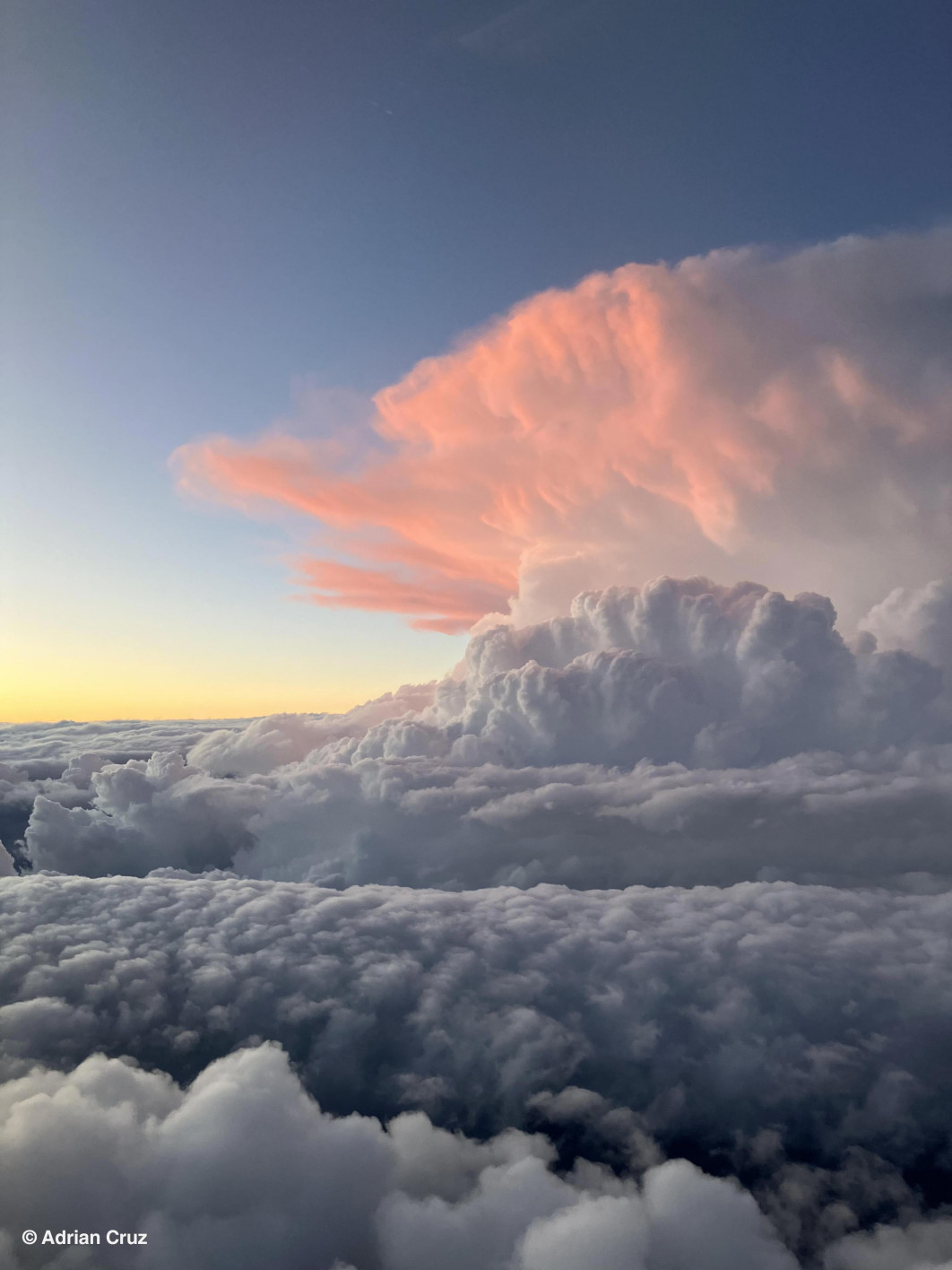 &lt;strong&gt;I miejsce w kat. poniżej 18 lat, fot. Adrian Cruz, USA &lt;/strong&gt;&lt;br /&gt;&lt;br /&gt;


Z pokładu samolotu pasażerskiego lecącego z Waszyngtonu do Orlando młody fotograf Adrian Cruz uchwycił niezwykły widok - burzową chmurę cumulonimbus, która świeci różowym blaskiem na tle pogrążającego się w granacie nieba. „Lecieliśmy obok burzy z piorunami - wyglądało to naprawdę niesamowicie” - wspomina autor zdjęcia.&lt;br /&gt;&lt;br /&gt;

Gigantyczna chmura widoczna na fotografii to klasyczny cumulonimbus, powstający w wyniku gwałtownego wznoszenia się ciepłego, wilgotnego powietrza. W miarę unoszenia się masa powietrza ochładza się, a para wodna kondensuje, tworząc wysokie kolumny chmur. Gdy prądy wstępujące są wyjątkowo silne, chmura może sięgać aż do tropopauzy - granicy między troposferą a stratosferą. Po osiągnięciu maksymalnej wysokości rozrasta się poziomo, przyjmując charakterystyczny kształt kowadła, widoczny na zdjęciu.&lt;br /&gt;&lt;br /&gt;

Różowe światło to efekt zachodzącego słońca. O tej porze dnia promienie słoneczne muszą przebyć dłuższą drogę przez atmosferę, przez co krótsze fale niebieskie rozpraszają się, a dłuższe - czerwone i pomarańczowe - dominują. Zjawisko to, znane jako rozpraszanie Rayleigha, nadaje chmurze subtelny, ciepły odcień. Jurorka Becky Mantin skomentowała: „To zdjęcie od razu przyciąga wzrok. Ta monumentalna ściana chmur kontrastująca z delikatnym, różowym światłem wygląda jak fragment krajobrazu, którego zwykle nie mamy okazji oglądać”.

