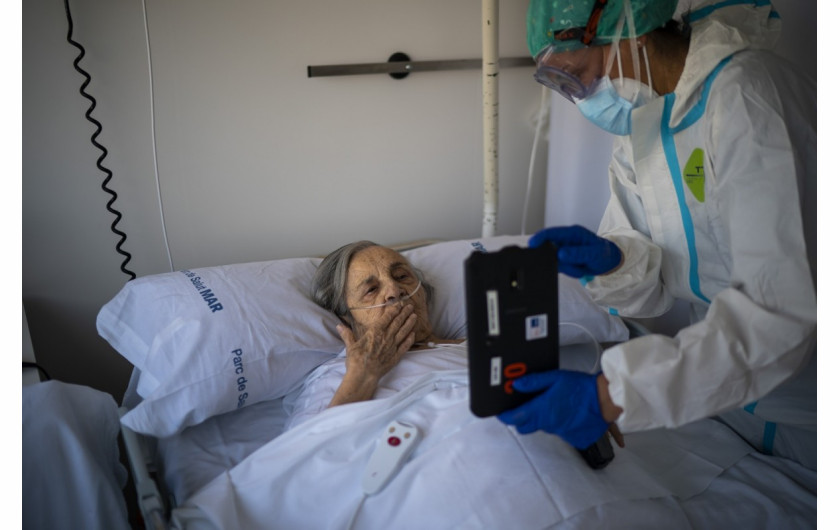 fot. Emilio Morenatti (Associated Press), Pielęgniarka Marta Fernandez trzyma tablet nad klatką piersiową 94-letniej Marii Teresy Argullos Bove, aby ta mogła porozmawiać ze swoją siostrą, dziećmi i wnukami z łóżka szpitalnego na oddziale COVID-19 w szpitalu del Mar w Barcelonie , Hiszpania, 18.11.2020. / The Pulitzer Prize 2021 for Feature Photography