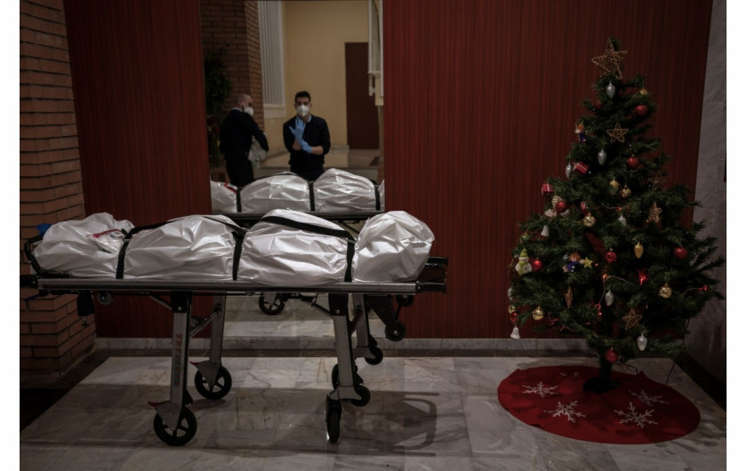 fot. Emilio Morenatti (Associated Press), Pracownicy kostnicy zdejmują odzież ochronną przy wejściu do budynku ozdobionego choinką. Na pierwszym planie ciało osoby podejrzanej o zgon na COVID-19, Barcelona, 23 grudnia 2020 r. / The Pulitzer Prize 2021 for Feature Photography