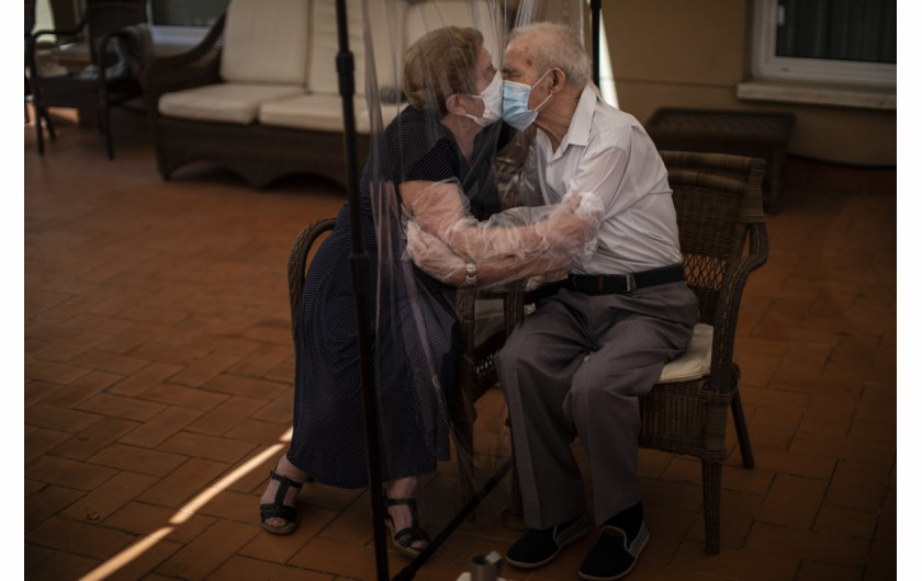 fot. Emilio Morenatti (Associated Press), 81-letnia Agustina Cañamero przytula i całuje swojego męża Pascuala Péreza (84 lata) przez plastikowy ekran, aby uniknąć zarażenia się koronawirusem w domu opieki w Barcelonie, Hiszpania, 22 czerwca 2020 roku. Strach, który ogarniał Agustinę Cañamero przez 102 dni, które ona i jej 84-letni mąż spędzili w separacji podczas epidemii koronawirusa w Hiszpanii zniknął w momencie, gdy para objęła się przez ekran z plastikowej folii. / The Pulitzer Prize 2021 for Feature Photography