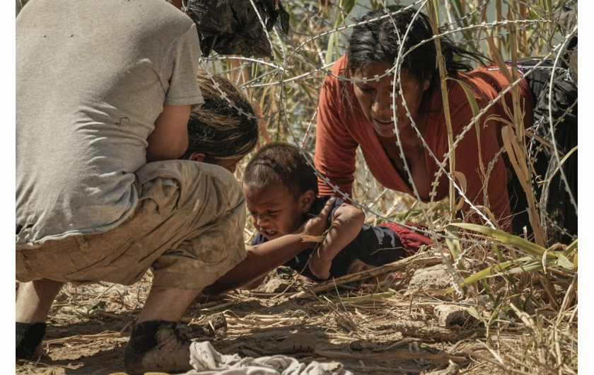 Wenezuelski migrant stoi przykryty folią podczas pisania SMS-a na brzegu Rio Grande w Matamoros w Meksyku, sobota, 13 maja 2023 r. (AP Photo/Fernando Llano)