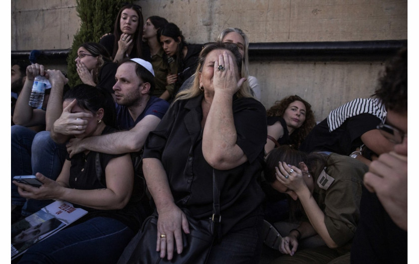 Przyjaciele i rodzina ukrywają się, gdy rozlegają się syreny rakietowe na pogrzebie Sagiva Ben Zvi, lat 24, który zginął kilka tygodni wcześniej na festiwalu Nova w wyniku infiltracji przez bojowników Hamasu, w Holon w Izraelu, 26 października 2023 r. (Zdjęcie: Evelyn Hockstein).