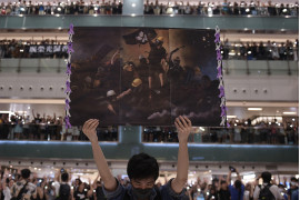 fot. Nicola Asfouti / Agence France Presse<br></br><br></br>Pierwsze protesty opanowały Hongkong pod koniec marca, były odpowiedzią na propozycje zmian przepisów i chęć wprowadzenia przez rządzących możliwości ekstradycji do Chin kontynentalnych. W kolejnych tygodniach demonstracje przybierały na sile, do protestujących grup prodemokratycznych dołączyli studenci. 12 czerwca dziesiątki tysięcy demonstrantów zgromadziły się wokół Rady Legislacyjnej pracujących nad nowelizacją zapisów o ekstradycji. W kolejnych dniach dochodziło do eskalacji z obydwu stron barykady. 1 października, w dniu 70. rocznicy deklaracji Chińskiej Republiki padły pierwsze strzały. Po początkowym zaproponowaniu odroczenia zmian w przepisach, dyrektor generalny Hongkongu Carrie Lam ostatecznie ogłosiła, że ​​wycofa projekt. Stało się to 23 października, ale żądania protestujących poszerzyły się o wprowadzenie powszechnych praw wyborczych i zwolnienie aresztowanych, napięta sytuacja trwa nadal.