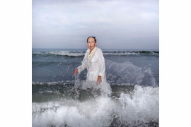 <b>Ana Nance, „Ostatni portret Mary Kay”, North Myrtle Beach, Południowa Karolina, USA.
</b><p>
Na południu Stanów Zjednoczonych wciąż kultywowany jest religijny rytuał baptystycznego Chrztu. Osoba chrzczona, ubrana na biało, wchodzi do wody, by oczyścić ciało i duszę. Na zdjęciu jest moja macocha Mary Kay, którą sfotografowałam w miejscu, w którym spędziłam wiele radosnych chwil dzieciństwa. Ten portret jest też hołdem dla mojego ojca, próbą odtworzenia zdjęcia, które zrobiłam mu wiele lat temu, tuż przed jego śmiercią. Ten chrzest nie ma nic wspólnego z religią - to pielęgnowanie pamięci, miłości i wdzięczności. To mój własny rytuał. Kay również zmarła na raka w październiku tego roku. To jest jej ostatni portret.
