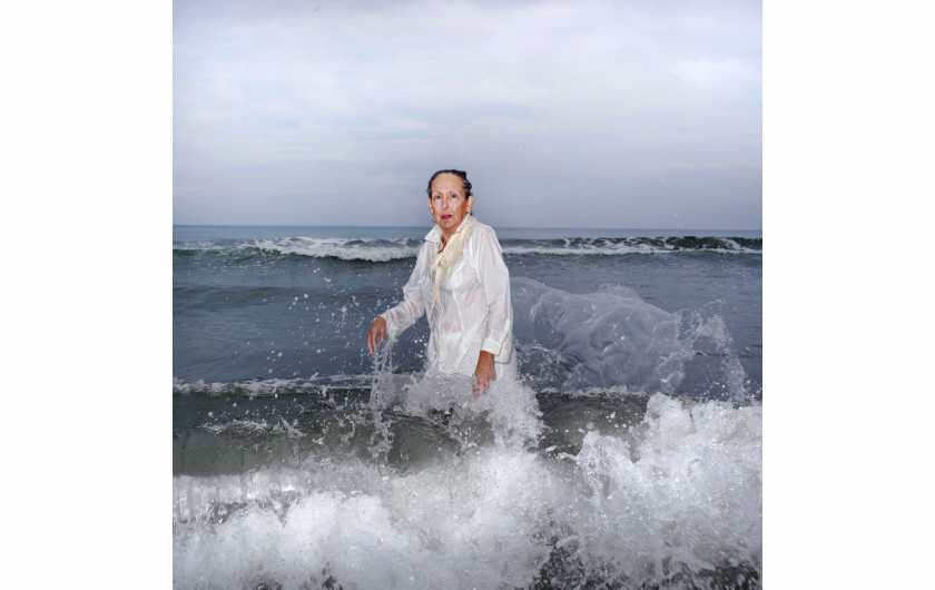 Ana Nance, „Ostatni portret Mary Kay”, North Myrtle Beach, Południowa Karolina, USA.

Na południu Stanów Zjednoczonych wciąż kultywowany jest religijny rytuał baptystycznego Chrztu. Osoba chrzczona, ubrana na biało, wchodzi do wody, by oczyścić ciało i duszę. Na zdjęciu jest moja macocha Mary Kay, którą sfotografowałam w miejscu, w którym spędziłam wiele radosnych chwil dzieciństwa. Ten portret jest też hołdem dla mojego ojca, próbą odtworzenia zdjęcia, które zrobiłam mu wiele lat temu, tuż przed jego śmiercią. Ten chrzest nie ma nic wspólnego z religią - to pielęgnowanie pamięci, miłości i wdzięczności. To mój własny rytuał. Kay również zmarła na raka w październiku tego roku. To jest jej ostatni portret.
