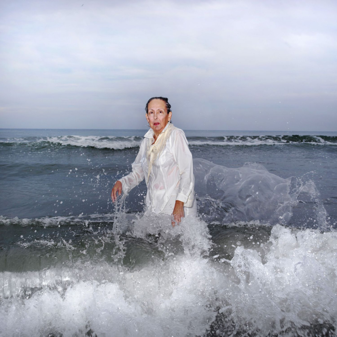 <b>Ana Nance, „Ostatni portret Mary Kay”, North Myrtle Beach, Południowa Karolina, USA.
</b><p>
Na południu Stanów Zjednoczonych wciąż kultywowany jest religijny rytuał baptystycznego Chrztu. Osoba chrzczona, ubrana na biało, wchodzi do wody, by oczyścić ciało i duszę. Na zdjęciu jest moja macocha Mary Kay, którą sfotografowałam w miejscu, w którym spędziłam wiele radosnych chwil dzieciństwa. Ten portret jest też hołdem dla mojego ojca, próbą odtworzenia zdjęcia, które zrobiłam mu wiele lat temu, tuż przed jego śmiercią. Ten chrzest nie ma nic wspólnego z religią - to pielęgnowanie pamięci, miłości i wdzięczności. To mój własny rytuał. Kay również zmarła na raka w październiku tego roku. To jest jej ostatni portret.
