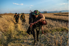 fot. Mauk Kham Wah, nominacja z regionu Azji Południowo-wschodniej i Oceanii<br></br><br></br>Bojownicy ruchu oporu z Ludowych Sił Obrony (PDF) wycofują się z ciałem towarzysza po starciu z birmańskim wojskiem w Moe Bye, Birma, 21 lutego 2022 r. Władze Birmy wysłały do tego regionu posiłki w związku z nasileniem się walk z lokalnymi grupami opozycyjnymi.
<br></br><br></br>
PDF walczy u boku regionalnych i etnicznych grup zbrojnych sprzeciwiających się dyktaturze wojskowej. Jest to zbrojne skrzydło równoległego rządu, który został utworzony głównie przez obalonych demokratycznych ustawodawców w następstwie wojskowego zamachu stanu w Myanmarze w 2021 roku. Z wielkim osobistym ryzykiem fotograf spędził rok z ludźmi, którzy dołączyli do ruchu oporu.