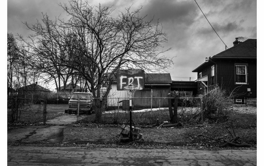 fot. Chris Donovan, Kanada, z cyklu: Those Who Stay Will Be Champions / World Press Photo 2021Drużyna koszykarska Flint Jaguars z Flint w stanie Michigan w USA uosabia wysiłki mające na celu pielęgnowanie stabilności, zachęcanie do wzajemnego wsparcia i wzmacnianie ducha wspólnoty w mieście walczącym o przetrwanie.Flint, miejsce narodzin General Motors, walczy z emigracją spowodowaną gwałtownym upadkiem przemysłu samochodowego, kryzysem zdrowotnym spowodowanym przez władze zmieniające źródła zaopatrzenia w wodę bez odpowiednich zabezpieczeń oraz systemowym zaniedbaniem.Koszykówka jest integralną częścią kultury Flint. Przez dziesięciolecia stale konkurowały tam ze sobą 4 licealne drużyny. Teraz w mieście została tylko jedna szkoła średnia. Flint Jaguars powstały w 2017 roku, łącząc zespoły dwóch ostatnich szkół, które przetrwały do tego czasu.W 2020 roku zespół walczył o odwrócenie złej passy. Do marca byli przygotowani do awansu do finału ligi, wygrywając więcej meczów niż łącznie w poprzednich trzech latach łącznie. Ich baraż zakończył się przedwcześnie, gdy COVID-19 wymusił odwołanie sezonu. Niemniej jednak sportowcy-studenci zasmakowali wspólnego sukcesu.