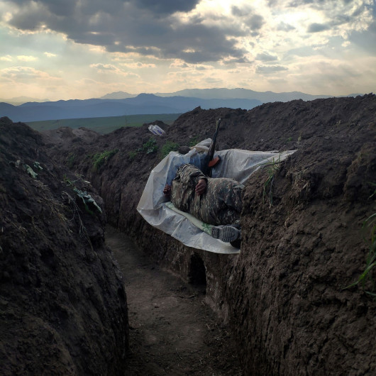 fot. Vaghinak Ghazaryan, Armenia, Resting Soldier, 3 miejsce w kategorii Contemporary issues - zdjęcie pojedyncze / World Press Photo 2021Żołnierz leży w rowie, wsparty na plastikowej osłonie, w północno-wschodniej części Syunikin, Armenia, 31 października 2020.Druga wojna o Górski Karabach rozpoczęła się 27 września, a konflikt trwał do 9 listopada. Był to największy konflikt między Armenią a Azerbejdżanem o sporne terytorium od lat 90 XX wieku. Pierwsza wojna zakończyła się niełatwym zawieszeniem broni, w wyniku którego zwycięscy Ormianie jednostronnie ogłosili niepodległość i wypędzili około 800 000 Azerów na wygnanie.W ciągu ostatnich 30 lat niewiele zrobiono, aby rozwiązać kwestię Górskiego Karabachu, który nadal był uznawany na arenie międzynarodowej za należący do Azerbejdżanu, a między obiema stronami dochodziło do okresowych starć zbrojnych, które w 2020 r. przerodziły się w wojnę.Dzięki Rosji w listopadzie Azerbejdżan odzyskał terytorium utracone w latach 90., ale stolica regionu Stepanakert pozostała pod kontrolą Armenii. Armia armeńska stopniowo wycofywała się z regionu Górskiego Karabachu, by zastąpić ją rosyjskimi siłami pokojowymi, które będą tam rozmieszczone do 2025 roku.