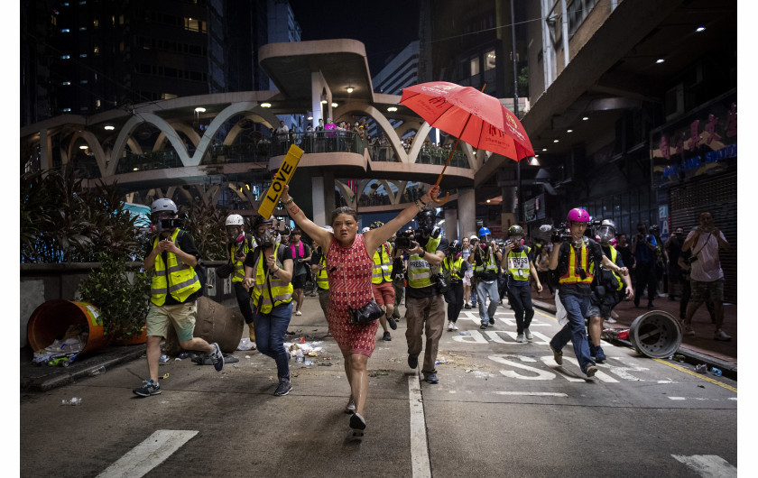 fot. Nicolas Afouri / Agence France-Presse, z cyklu Hong Kong Unrest,1. miejsce w kategorii General NewsPierwsze protesty opanowały Hongkong pod koniec marca, były odpowiedzią na propozycje zmian przepisów i chęć wprowadzenia przez rządzących możliwości ekstradycji do Chin kontynentalnych. W kolejnych tygodniach demonstracje przybierały na sile, do protestujących grup prodemokratycznych dołączyli studenci. 12 czerwca dziesiątki tysięcy demonstrantów zgromadziły się wokół Rady Legislacyjnej pracujących nad nowelizacją zapisów o ekstradycji. W kolejnych dniach dochodziło do eskalacji z obydwu stron barykady. 1 października, w dniu 70. rocznicy deklaracji Chińskiej Republiki padły pierwsze strzały. Po początkowym zaproponowaniu odroczenia zmian w przepisach, dyrektor generalny Hongkongu Carrie Lam ostatecznie ogłosiła, że ​​wycofa projekt. Stało się to 23 października, ale żądania protestujących poszerzyły się o wprowadzenie powszechnych praw wyborczych i zwolnienie aresztowanych, napięta sytuacja trwa nadal.