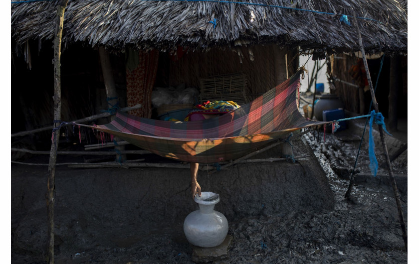 fot. K M Asad, Bangladesz, Climate Crisis Solutions: Collecting Drinking Water in Kalabogi, nominacja w kategorii Środowisko - zdjęcie pojedyncze / World Press Photo 2021Kobieta czerpie wodę pitną ze szmatki wystawionej na poranną rosę we wsi Kalabogi, w lasach namorzynowych Sundarbans w Zatoce Bengalskiej w Bangladeszu, 27 września 2020 r.Mieszkańcy Kalabogi i regionu Sundarbans cierpią na niedobór wody w porze suchej w wyniku rosnącego zasolenia wód gruntowych i rzeki Satkhira, spowodowanego podnoszącym się poziomem mórz. Domy we wsiach takich jak Kalabogi wznosi się na słupach, aby uniknąć częstych powodzi.W raporcie Banku Światowego z 2016 r. stwierdzono, że kryzys klimatyczny stwarza szereg zagrożeń dla Sundarbanów, w tym podnoszenie się poziomu mórz oraz częstotliwość i intensywność burz. Satelity odkryły, że w niektórych częściach regionu poziom morza przesuwa się o 200 metrów rocznie. Badania naukowe wskazują, że około 20 milionów ludzi mieszkających na wybrzeżu Bangladeszu jest dotkniętych zasoleniem wody pitnej. Ponad połowa obszarów przybrzeżnych jest dotknięta zasoleniem, które zmniejsza produktywność gleby i wzrost roślinności, degradując środowisko i wpływając na życie i źródła utrzymania ludzi. Pola ryżowe i grunty uprawne są przekształcane w hodowle krewetek, co dodatkowo przyczynia się do zasolenia wód gruntowych i degradacji gleby.