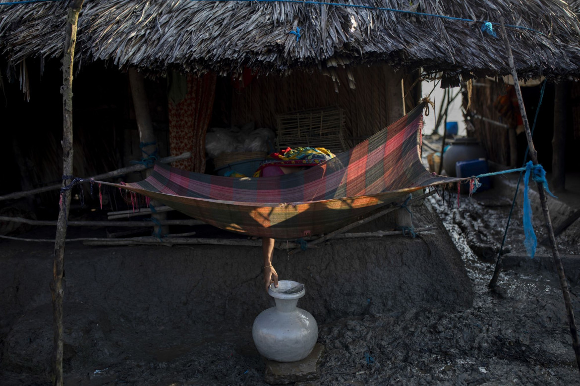 fot. K M Asad, Bangladesz, "Climate Crisis Solutions: Collecting Drinking Water in Kalabogi", nominacja w kategorii Środowisko - zdjęcie pojedyncze / World Press Photo 2021<br></br><br></br>Kobieta czerpie wodę pitną ze szmatki wystawionej na poranną rosę we wsi Kalabogi, w lasach namorzynowych Sundarbans w Zatoce Bengalskiej w Bangladeszu, 27 września 2020 r.<br></br><br></br>Mieszkańcy Kalabogi i regionu Sundarbans cierpią na niedobór wody w porze suchej w wyniku rosnącego zasolenia wód gruntowych i rzeki Satkhira, spowodowanego podnoszącym się poziomem mórz. Domy we wsiach takich jak Kalabogi wznosi się na słupach, aby uniknąć częstych powodzi.<br></br><br></br>W raporcie Banku Światowego z 2016 r. stwierdzono, że kryzys klimatyczny stwarza szereg zagrożeń dla Sundarbanów, w tym podnoszenie się poziomu mórz oraz częstotliwość i intensywność burz. Satelity odkryły, że w niektórych częściach regionu poziom morza przesuwa się o 200 metrów rocznie. Badania naukowe wskazują, że około 20 milionów ludzi mieszkających na wybrzeżu Bangladeszu jest dotkniętych zasoleniem wody pitnej. Ponad połowa obszarów przybrzeżnych jest dotknięta zasoleniem, które zmniejsza produktywność gleby i wzrost roślinności, degradując środowisko i wpływając na życie i źródła utrzymania ludzi. Pola ryżowe i grunty uprawne są przekształcane w hodowle krewetek, co dodatkowo przyczynia się do zasolenia wód gruntowych i degradacji gleby.