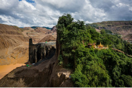 fot. Hkun Lat, Birma, "Temple and Half-Mountain", 2 miejsce w kategorii Środowisko - zdjęcie pojedyncze / World Press Photo 2021<br></br><br></br>Świątynia buddyjska zajmuje połowę góry, podczas gdy druga połowa została rozkuta przez ciężkie maszyny wydobywające jadeit w Hpakant w stanie Kaczin w Birmie, 15 lipca 2020 r.<br></br><br></br>Hpakant to miejsce, w którym znajduje się największa na świecie kopalnia jadeitu. Przemysł napędzają Chiny, gdzie jadeit jest popularnym symbolem statusu. Firma Global Witness poinformowała, że ​​tylko w 2014 roku rynek jadeitu w Birmie był wart 31 miliardów dolarów - prawie połowę PKB kraju - i że sektor ten wydawał się być kontrolowany przez sieci elit wojskowych oraz handlarzy narkotyków.<br></br><br></br>Rząd Narodowej Ligi na rzecz Demokracji (NLD) obiecał rozwiązać problemy w tym sektorze, ale postępy są powolne. Firmy nie spełniają wymogów rządowych, aby przeprowadzić ocenę oddziaływania na środowisko zgodnie z międzynarodowymi standardami, a urzędnicy rzekomo mają związane ręce.<br></br><br></br>Niszczenie środowiska przez działalność górniczą obejmuje m.in. masową utratę roślinności, degradację gruntów rolnych oraz zanieczyszczanie rzek i jest głównie wynikiem niewłaściwych praktyk górniczych. W Hpakant problem potęgują wysokie hałdy odpadów wydobywczych, rozległe opuszczone wyrobiska oraz firmy, które nie potrafią ustabilizować głębokich wykopów. Osuwiska, takie jak lawina błotna w lipcu 2020 r., w której zginęło co najmniej 100 osób nie należą do rzadkości.