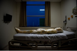 Joshua Irwandi, Indonezja, "The Human Cost of COVID-19", 2 miejsce w kategorii General news - zdjęcie pojedyncze / World Press Photo 2021<br></br><br></br>Ciało ofiary koronawirusa, owinięte w żółty plastik, czeka na torbę na zwłoki w szpitalu w Indonezji 18 kwietnia 2020 r.<br></br><br></br>Pielęgniarki owinęły ciało plastikiem i spryskały je środkiem dezynfekującym, zgodnie z protokołami indonezyjskiego rządu. Protokoły te wymagają owijania ciał ofiar COVID-19 w plastik i szybkiego pochówku, aby zapobiec rozprzestrzenianiu się wirusa. Oznaczało to, że pogrążeni w żałobie krewni nie są w stanie przestrzegać muzułmańskich praktyk pogrzebowych, które obejmują osobiste mycie zmarłych i owijanie zwłok w bezszwową szmatkę.<br></br><br></br>Światowa Organizacja Zdrowia odradzała stosowanie środków dezynfekujących i zalecała owijanie korpusów tkaniną. Potencjalne ryzyko przeniesienia choroby związane z obchodzeniem się z ciałami ofiar COVID-19 uważa się za niskie, pod warunkiem, że jest ono przeprowadzane przez przeszkolony personel medyczny noszący, odpowiednie środki ochrony.<br></br><br></br>Na całym świecie sprawę COVID-19 pogorszyły dezinformacja i nieodpowiednie raporty. Dla wielu brak dostępu do faktów i dokładnych, opartych na nauce wiadomości na temat choroby doprowadził do dezorientacji, niepokoju i wyparcia. Opublikowanie tego zdjęcia wywołało silną reakcję w mediach społecznościowych. Wielu oświadczyło, że jest to manipulacja mająca na celu szerzenie strachu. Do końca roku Indonezja zgłosiła około 743 000 przypadków COVID-19 i ponad 22 000 zgonów.