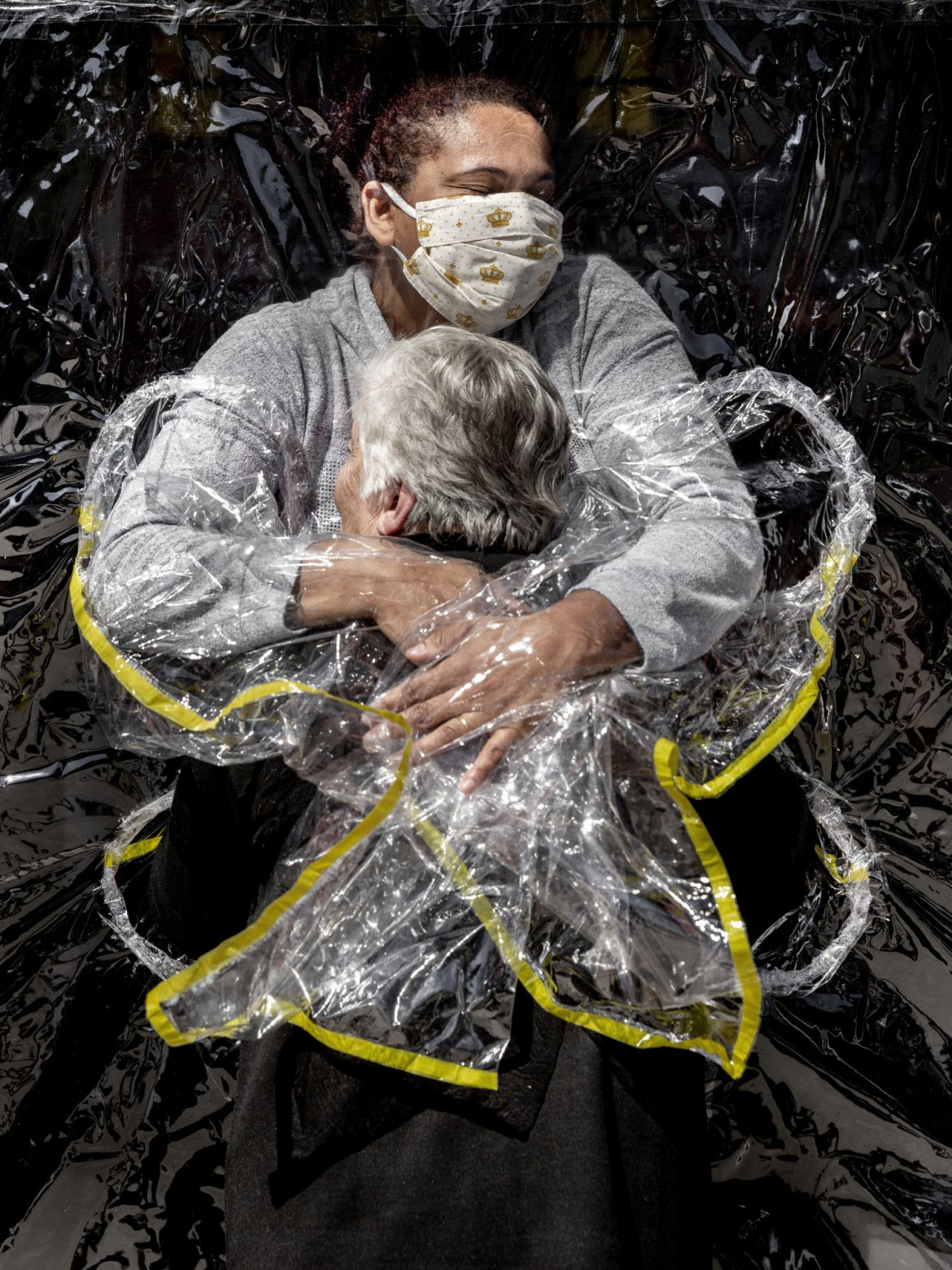 fot. Mads Nissen, Dania, "The First Embrace", nominacja w kategorii General News - zdjęcie pojedyncze / World Press Photo 2021<br></br><br></br>To był pierwszy uścisk, który Rosa otrzymała od pięciu miesięcy. W marcu domy opieki w całym kraju zamknęły swoje drzwi dla odwiedzających w wyniku pandemii COVID-19, uniemożliwiając milionom Brazylijczyków zobaczenie swoich krewnych. Opiekunom nakazano utrzymywać kontakt fizyczny z osobami postronnymi do absolutnego minimum. W Viva Bem prosty wynalazek „Zasłona uścisku” pozwolił ludziom ponownie się przytulić.<br></br><br></br>Nowy koronawirus pojawił się po raz pierwszy w Wuhan w Chinach pod koniec 2019 roku, a od stycznia 2020 roku zaczął rozprzestrzeniać się na całym świecie. 11 marca Światowa Organizacja Zdrowia ogłosiła wybuch COVID-19 pandemią. Choroba - przenoszona głównie przez bliski kontakt, kropelki oddechowe i aerozole - może być śmiertelna, a osoby w wieku powyżej 70 lat są jedną z grup uważanych za najbardziej narażone na infekcję.<br></br><br></br>Prezydent Brazylii Jair Bolsonaro odrzucił twierdzenia o powadze pandemii i niebezpieczeństwie, jakie stwarza wirus, podważał środki kwarantanny przyjęte na szczeblu stanowym i zachęcał Brazylijczyków do dalszych działań na rzecz utrzymania gospodarki. Brazylia zakończyła rok 2020 jednym z najgorszych na świecie rekordów w walce z wirusem, z około 7,7 miliona zgłoszonych przypadków i 195000 zgonów.