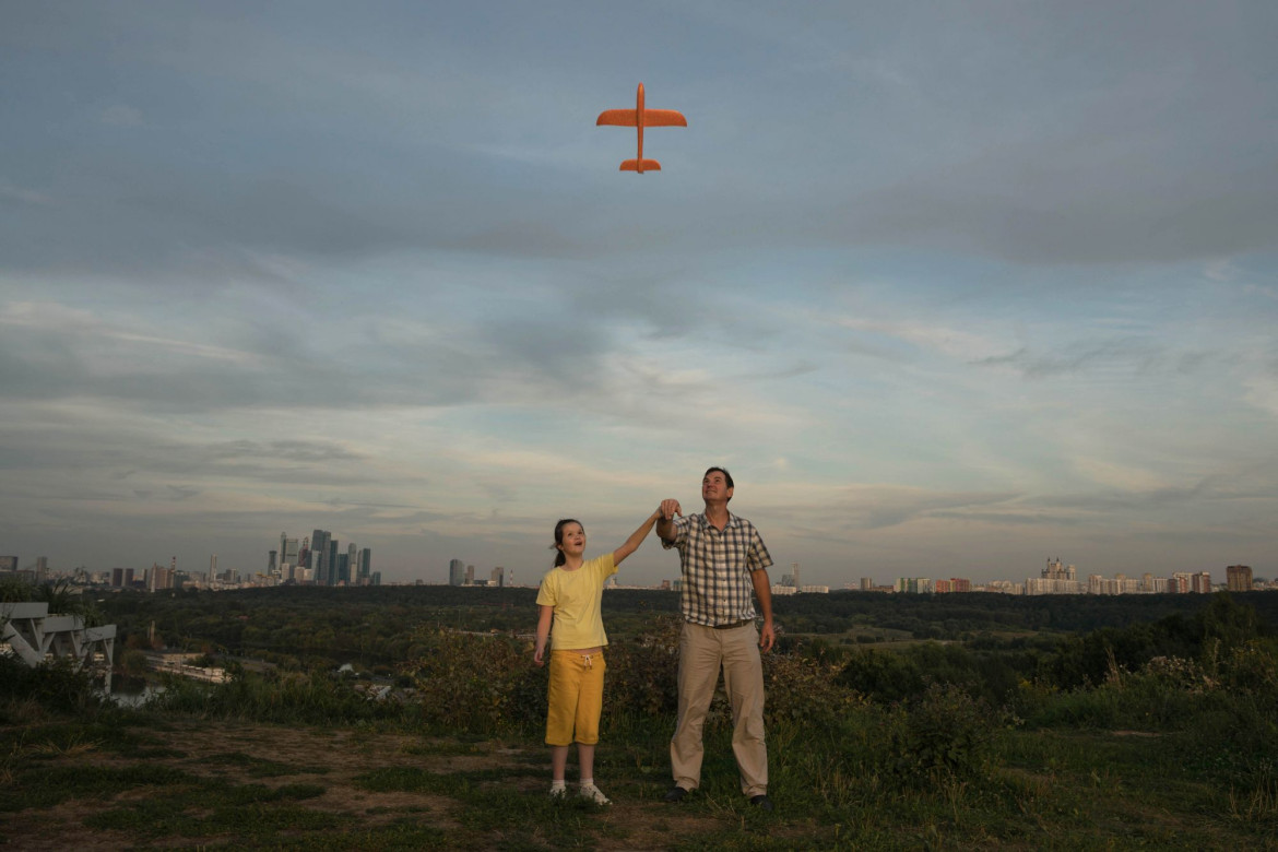 fot. Tatiana Nikitina, Rosja, "In Flight", 3 miejsce w kategorii Portret - zdjęcie pojedyncze / World Press Photo 2021<br></br><br></br>Ojciec uczy swoją autystyczną córkę Ksenię (10 l.), jak uruchomić zabawkowy samolot w Moskwie, w Rosji, 23 sierpnia 2020 r.<br></br><br></br>Zaburzenia ze spektrum autyzmu (ASD) to zaburzenie rozwojowe, które wpływają na komunikację i zachowanie. Nazywa się to zaburzeniem „spektrum”, ponieważ istnieje duże zróżnicowanie w rodzaju i nasileniu objawów, których doświadczają ludzie. Osoby ze spektrum autyzmu mogą mieć trudności z komunikacją i interakcją z innymi ludźmi, wykazywać ograniczone zainteresowania i powtarzające się zachowania oraz mogą reagować impulsywnie na bodźce środowiskowe, co oznacza, że ​​może im być trudniej dobrze funkcjonować w pracy, szkole lub w szkole.<br></br><br></br>Pojęcie autyzmu jest w Rosji całkiem nowe, często występuje negatywny stosunek do osób z takimi zaburzeniami zachowania. Niewielu lekarzy i nie-lekarzy jest zaznajomionych z autyzmem i często jest on błędnie diagnozowany. Rodzice dzieci z ASD mogą mieć trudności ze znalezieniem programów wsparcia.