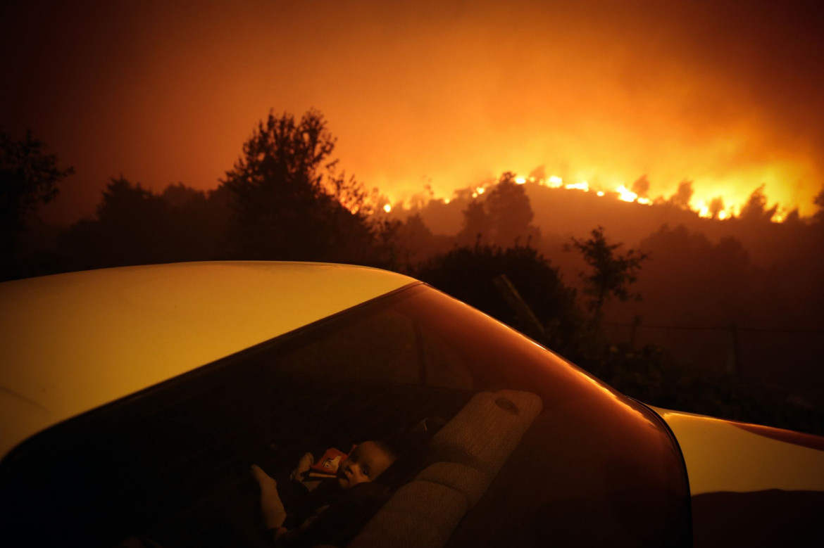 fot. Nuno André Ferreira, Portugalia, "Forest Fire", nominacja w kategorii Spot news - zdjęcie pojedyncze / World Press Photo 2021<br></br><br></br>Dziecko siedzi w samochodzie nieopodal pożaru lasu w Oliveira de Frades, w Portugalii, 7 września 2020 r.<br></br><br></br>Pożar w Oliveira de Frades, około 100 kilometrów od Porto we wschodniej Portugalii, wybuchł 7 września i rozprzestrzenił się około 30 kilometrów na zachód 40 kilometrów na południowy zachód w sąsiednim okręgu. Co najmniej 300 strażaków, 100 pojazdów lądowych i 10 samolotów strażackich walczyło z pożarem w krajobrazie zdominowanym przez drzewa eukaliptusowe.<br></br><br></br>Niekontrolowane rozprzestrzenianie się drzew eukaliptusowych - które dostarczają surowca dla ważnego gospodarczo przemysłu celulozowego, ale które są wyjątkowo łatwopalne - są głównym czynnikiem szybkiego rozprzestrzeniania się pożarów. W Portugalii okres pożarów trwa od czerwca do września. Gorący klimat, stałe ciepłe wiatry znad Atlantyku i dobrze zalesiony krajobraz sprawiają, że region ten jest szczególnie podatny na pożary.<br></br><br></br>Ekstremalne temperatury i dotkliwa susza przyczyniły się do pożarów w2020. W raporcie opublikowanym wspólnie przez Portugalskie Stowarzyszenie Przyrody i Światowy Fundusz na rzecz Przyrody stwierdzono, że Portugalia jest najbardziej dotkniętym pożarami krajem europejskim: każdego roku spala się ponad trzy procent lasów.