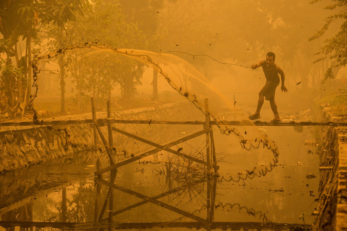 fot. Björn Vaughn (finalista), “Better a dirt fish than no fish at all!”, Za sprawą pożarów torfu w Indonezji, cały region Kalimantan pokrywa toksyczny smog. Mimo to wędkarz łowi ryby w skażonym kanale.