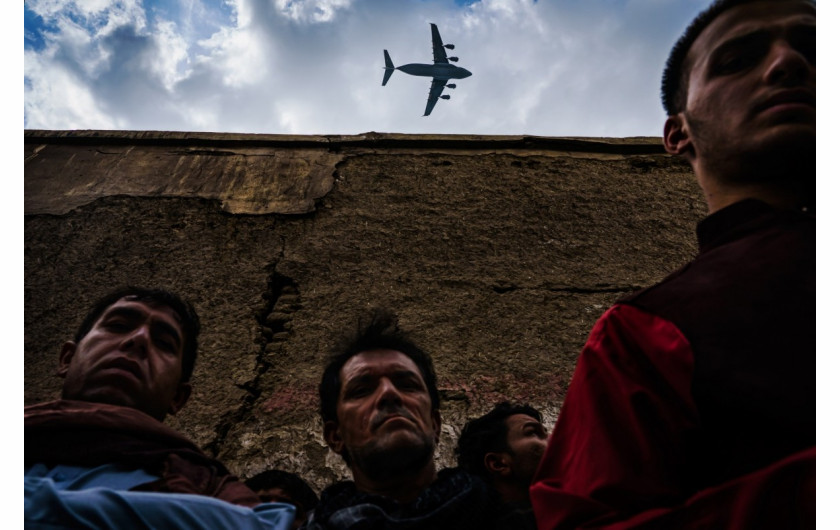 fot. Marcus Yam / LA Times, Wojskowy samolot transportowy przelatuje nad krewnymi i sąsiadami rodziny Ahmadi, zgromadzonej wokół pojazdu zniszczonego przez amerykański atak dronów w Kabulu / Pulitzer Prize 2021 for Breaking News Photography