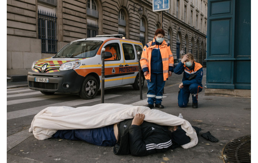 fot. Laurence Geai, Francja, z cyklu: COVID-19 Pandemic in France, nominacja w kategorii General news - seria zdjęć / World Press Photo 2021

Pierwsze potwierdzone przypadki zachorowań na COVID-19 w Europie odnotowano we Francji w dniu 24 stycznia. Szybko pojawiły się doniesienia o zakażeniach w innych krajach europejskich, a 13 marca Światowa Organizacja Zdrowia ogłosiła Europę epicentrum pandemii. Do końca marca w Paryżu i na jego przedmieściach odnotowano ponad jedną czwartą z 29 000 potwierdzonych zakażeń we francuskich szpitalach, z czego 1300 osób przebywało na intensywnej terapii. Między 17 marca a 11 maja Francja ogłosiła lockdown, a ograniczenia w Paryżu przedłużono do 14 czerwca. Zamknięto szkoły, kawiarnie, restauracje, sklepy i budynki użyteczności publicznej, a osoby przebywające poza domem musiały mieć przy sobie dowód tożsamości i podpisane oświadczenie o podróżowaniu. Domy opieki zostały zamknięte dla odwiedzających. Hospitalizacje osiągnęły szczyt w kwietniu, kiedy to 7,148 osób znalazło się na intensywnej terapii, podczas gdy pojemność oddziałów wynosiła tylko 5,000. Specjalnie przystosowane pociągi przewoziły pacjentów z przepełnionych szpitali do regionów, w których było mniej przypadków, a francuskie wojsko lotnicze przewoziło krytyczne przypadki ze wschodniej Francji do szpitali w sąsiednich krajach. W miarę wzrostu liczby zgonów kostnice zapełniały się po brzegi, a w miejscach takich jak hala chłodnicza paryskiego rynku hurtowego żywności Rungis otwierano doraźne kostnice. Domom pogrzebowym nakazano natychmiastowe pochowanie lub skremowanie ciał, bez żadnych ceremonii pogrzebowych, bez niczyjej obecności.
