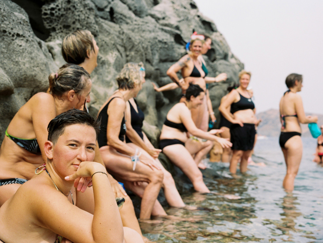 Fot. Florence Bass, "The Rock Ceremony" / Female in Focus x Nikon vol. 5<br></br>To zdjęcie jest częścią serii dokumentującej społeczność lesbijek w Lesbos. Zostało zrobione podczas ceremonii na skale Sappho z okazji lesbijskiego Nowego Roku. Podczas ceremonii kobiety wypływają na skałę z workiem popiołu zawierającym szczątki listów miłosnych, które z tego czy innego powodu chcą zostawić w przeszłości. Następnie każda z kobiet wsypuje popiół do morza w nadziei na oczyszczenie.