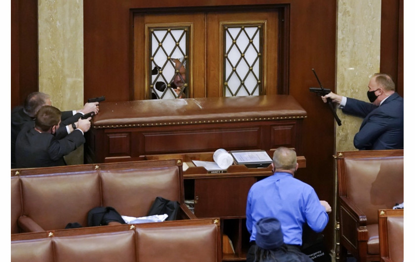 Policjanci Kapitolu kierują broń w stronę drzwi Izby Reprezentantów, podczas próby wyważenia, 6 stycznia 2021 r. w Waszyngtonie. fot. Drew Angerer, Getty Images / Pulitzer Prize 2021 for Breaking News Photography