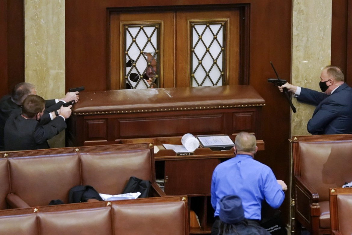 Policjanci Kapitolu kierują broń w stronę drzwi Izby Reprezentantów, podczas próby wyważenia, 6 stycznia 2021 r. w Waszyngtonie. fot. Drew Angerer, Getty Images / Pulitzer Prize 2021 for Breaking News Photography