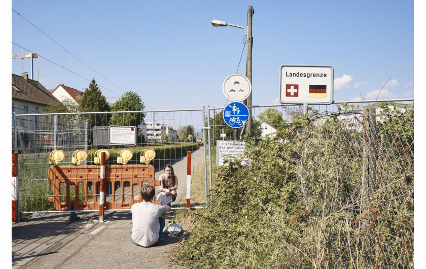 fot. Roland Schmid, Szwajcaria, z cyklu: Cross-Border Love, 2 miejsce w kategorii General news - seria zdjęć  / World Press Photo 2021


Szwajcaria zamknęła swoje granice po raz pierwszy od II wojny światowej w związku z pandemią COVID-19. W miastach takich jak Riehen i Kreuzlingen mieszkańcy od dziesięcioleci nie zwracali uwagi na granice z Niemcami i swobodnie je przekraczali. Zamknięcie trwało od 16 marca do 15 czerwca. Taśmy zaporowe wskazywały granice, których nie wolno było przekraczać, odtwarzając granice, które w czasie wojny zostały wzmocnione drutem kolczastym. W niektórych miejscach bariery te stały się miejscem spotkań ludzi, którym nie wolno już było przebywać razem. Mimo przepisów ograniczających poruszanie się i kontakty towarzyskie, wiele osób znajdowało pomysłowe sposoby, by spotkać się z bliskimi.