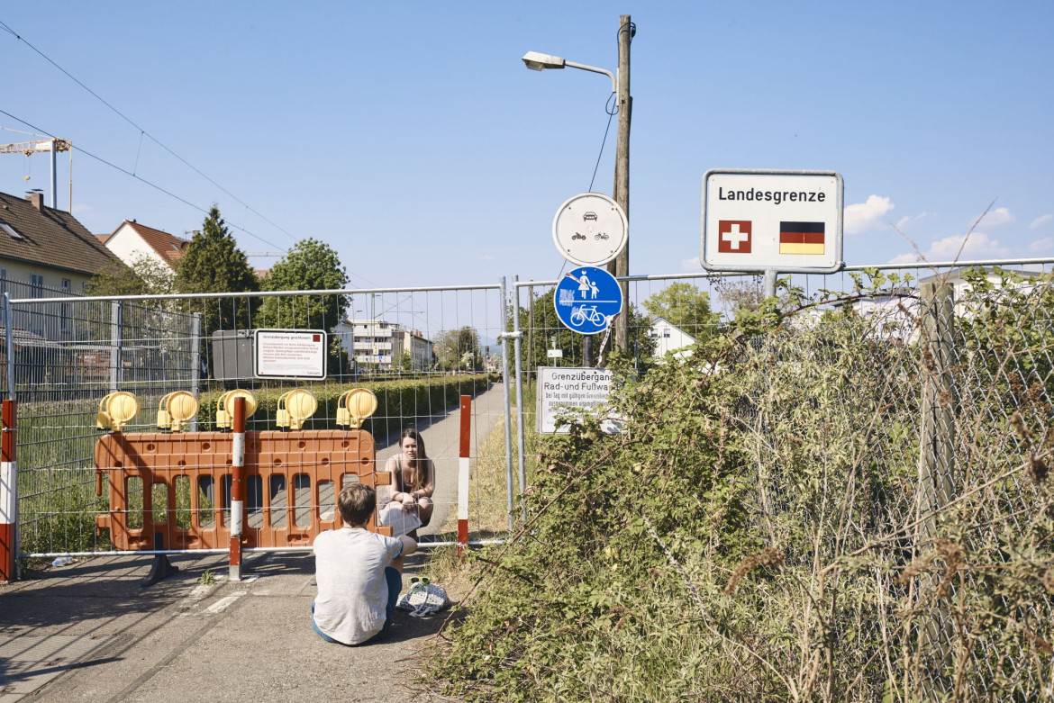 fot. Roland Schmid, Szwajcaria, z cyklu: "Cross-Border Love", 2 miejsce w kategorii "General news - seria zdjęć"  / World Press Photo 2021
<br></br><br></br>

Szwajcaria zamknęła swoje granice po raz pierwszy od II wojny światowej w związku z pandemią COVID-19. W miastach takich jak Riehen i Kreuzlingen mieszkańcy od dziesięcioleci nie zwracali uwagi na granice z Niemcami i swobodnie je przekraczali. Zamknięcie trwało od 16 marca do 15 czerwca. Taśmy zaporowe wskazywały granice, których nie wolno było przekraczać, odtwarzając granice, które w czasie wojny zostały wzmocnione drutem kolczastym. W niektórych miejscach bariery te stały się miejscem spotkań ludzi, którym nie wolno już było przebywać razem. Mimo przepisów ograniczających poruszanie się i kontakty towarzyskie, wiele osób znajdowało pomysłowe sposoby, by spotkać się z bliskimi.