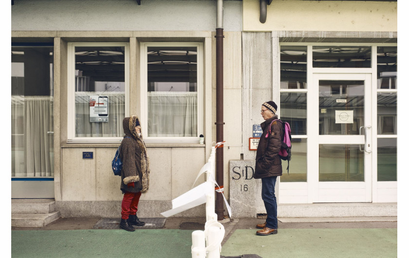 fot. Roland Schmid, Szwajcaria, z cyklu: Cross-Border Love, 2 miejsce w kategorii General news - seria zdjęć  / World Press Photo 2021


Szwajcaria zamknęła swoje granice po raz pierwszy od II wojny światowej w związku z pandemią COVID-19. W miastach takich jak Riehen i Kreuzlingen mieszkańcy od dziesięcioleci nie zwracali uwagi na granice z Niemcami i swobodnie je przekraczali. Zamknięcie trwało od 16 marca do 15 czerwca. Taśmy zaporowe wskazywały granice, których nie wolno było przekraczać, odtwarzając granice, które w czasie wojny zostały wzmocnione drutem kolczastym. W niektórych miejscach bariery te stały się miejscem spotkań ludzi, którym nie wolno już było przebywać razem. Mimo przepisów ograniczających poruszanie się i kontakty towarzyskie, wiele osób znajdowało pomysłowe sposoby, by spotkać się z bliskimi.