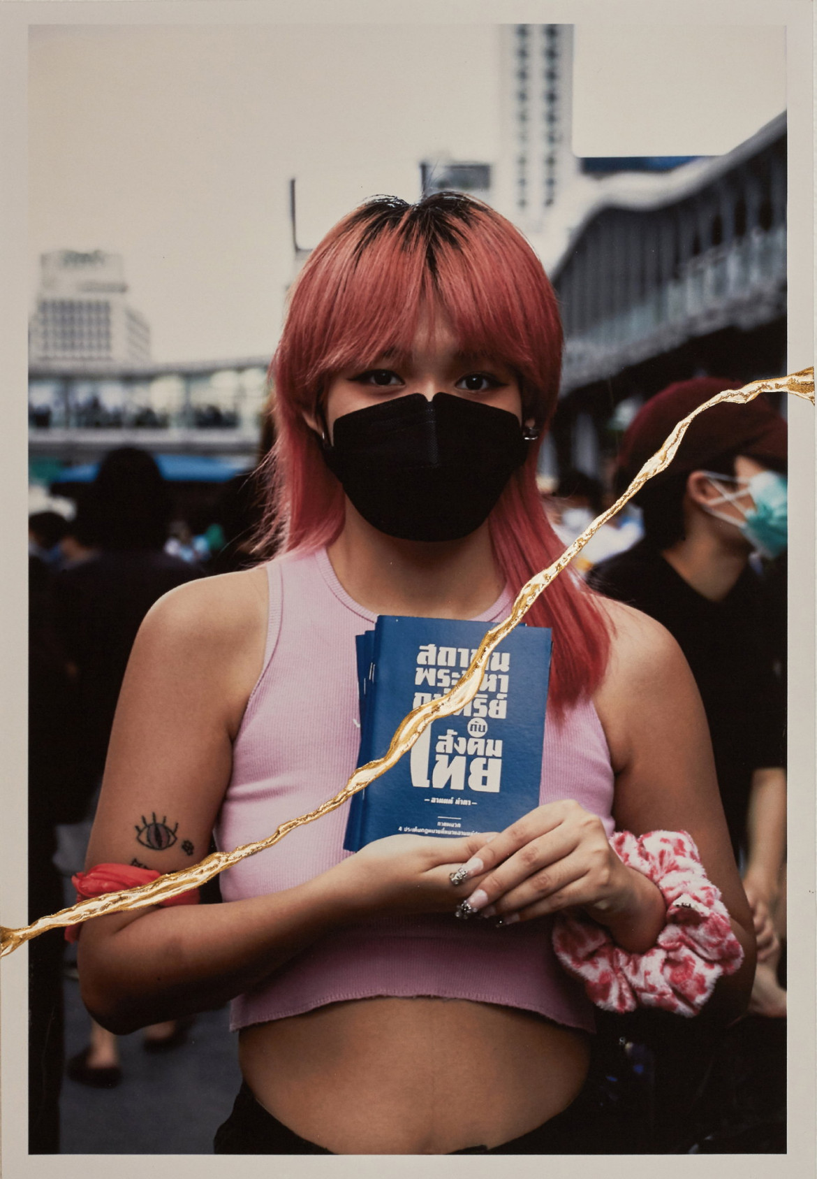 fot. Charinthorn Rachurutchata, z cyklu "The Will to Remember"
<br><br>
Student trzeciego roku Uniwersytetu Thammasat bierze udział w proteście prodemokratycznym w Bangkoku, Tajlandia.
<br><br>
W projekcie zestawiono archiwalne zdjęcia masakry studentów na Uniwersytecie Thammasat w Bangkoku z 6 października 1976 r. z fotografiami, które Rachurutchata wykonał podczas protestów w Tajlandii w latach 2020-2022, aby zrozumieć przyczyny współczesnych protestów. Fotograf naśladuje japońską sztukę kintsugi, rozdzierając zdjęcia, a następnie naprawiając je lakierem i sproszkowanym złotem. Rachurutchata wykorzystuje kintsugi, by symbolizować przemianę traumy w nadzieję na lepszą przyszłość.