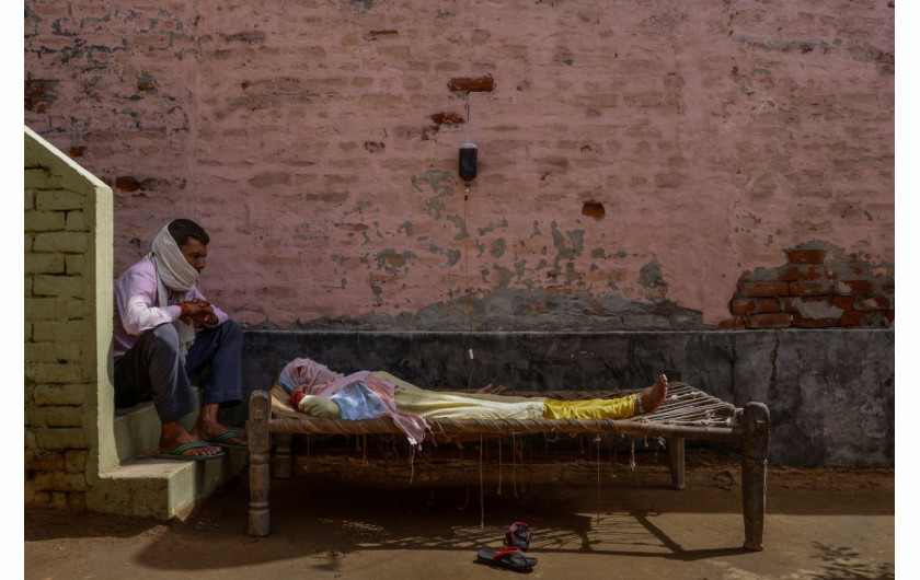 Mężczyzna przesiaduje obok chorej żony w prowizorycznej klinice w wiosce Parsaul, w stanie Uttar Pradesh w Indiach, 22 maja 2021 r. fot. Adnan Abidi, Reuters / The Pulitzer Prize 2021 for Feature Photography