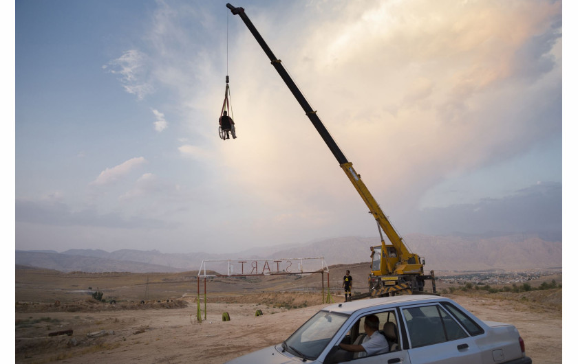 fot. Fereshteh Eslahi, Iran, Podium Photos, z cyklu: Thoughts of Flight, nominacja w kategorii Sport - seria zdjęć / World Press Photo 2021

Saeed Ramin jest zawodowym traceurem (uprawiającym parkour) mieszkającym w Gachsaran w Iranie. Siedem lat temu Saeed upadł podczas zawodów w parkourze, uszkadzając rdzeń kręgowy w szyi. Celem parkour jest przedostanie się z jednego punktu do drugiego w złożonym - zazwyczaj miejskim - otoczeniu, bez pomocy sprzętu pomocniczego, w jak najszybszy i najbardziej efektywny sposób: biegając, huśtając, wspinając się i wykonując wiele innych ruchów, czasem w niebezpiecznych sytuacjach, takich jak przechodzenie między wysokimi dachami. Dyscyplina ta została spopularyzowana w późnych latach 90. i 2000 poprzez filmy, gry wideo, filmy dokumentalne i reklamy, a stała się popularna w Iranie po tym, jak dwóch irańskich traceurów pojawiło się w filmie dokumentalnym Jump London. Uraz Saeeda po upadku był tak poważny, że mógł on tylko mrugać, a lekarze powiedzieli, że nie będzie w stanie nawet usiąść na wózku inwalidzkim. Saeed nie mógł sobie pozwolić na dłuższe leczenie szpitalne, ale z pomocą rodziny zaimprowizował sprzęt rehabilitacyjny na swoim podwórku i wbrew przewidywaniom lekarzy udało mu się odzyskać sprawność rąk. Saeed odzyskał więcej swoich zdolności, a teraz jest w stanie poradzić sobie z wózkiem inwalidzkim. Nadal lubi robić rzeczy, których inni ludzie się boją.
