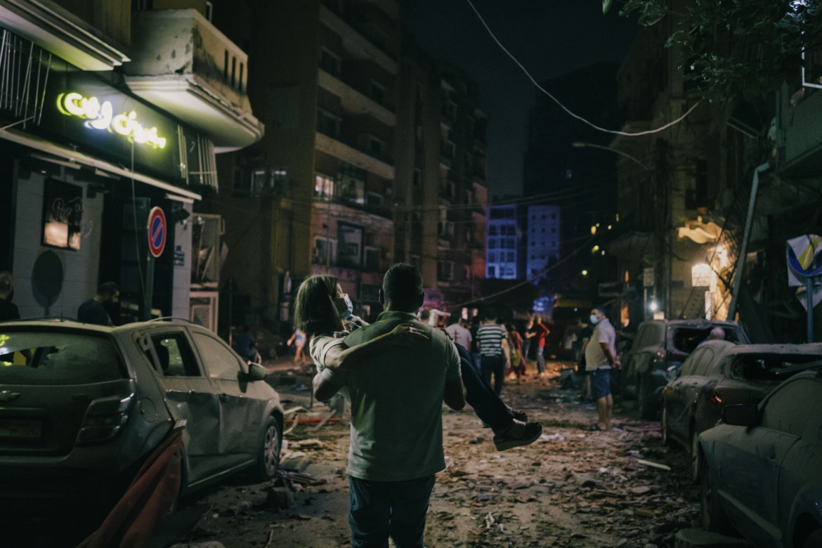 fot. 
Lorenzo Tugnoli, Włochy, Contrasto, Z cyklu: "Port Explosion in Beirut", nominacja w kategorii "Spot news - seria zdjęć"  / World Press Photo 2021<br></br><br></br>

Około godziny 18:00, 4 sierpnia, potężna eksplozja, spowodowana przez ponad 2750 ton azotanu amonu o wysokiej gęstości, wstrząsnęła stolicą Libanu, Bejrutem. Mieszanka wybuchowa była przechowywana w magazynie w porcie. W promieniu kilometra od magazynu mieszkało około 100 000 osób. Eksplozja, która miała siłę 3,3 stopnia w skali Richtera, uszkodziła lub zniszczyła około 6 tysięcy budynków, zabiła co najmniej 190 osób, zraniła kolejne 6 tysięcy, a 300 tysięcy wysiedliła. Azotan amonu pochodził ze statku, który został skonfiskowany w 2012 r. za nieuiszczenie opłat za dokowanie i innych opłat, i najwyraźniej porzucony przez właściciela. W latach 2014-2017 urzędnicy celni co najmniej sześć razy pisali do libańskich sądów z pytaniem, jak pozbyć się materiału wybuchowego. W międzyczasie był on przechowywany w magazynie w nieodpowiednim klimacie. Nie jest jasne, co spowodowało eksplozję, ale najbardziej prawdopodobną przyczyną wydaje się zanieczyszczenie innymi substancjami podczas transportu lub przechowywania. Wielu obywateli uznało ten incydent za symptom ciągłych problemów, z jakimi boryka się kraj, a mianowicie nieudolności rządu, niegospodarności i korupcji. W kilka dni po wybuchu dziesiątki tysięcy demonstrantów wypełniły ulice centrum Bejrutu, niektórzy starli się z siłami bezpieczeństwa i zajęli budynki rządowe, protestując przeciwko systemowi politycznemu, który ich zdaniem nie chce rozwiązać problemów kraju.