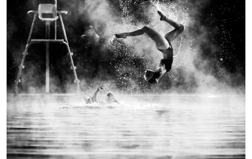 fot. James Rokop, Synchro Steam, wyróżnienie w kat. Sports in Action / Siena International Photo Awards 2020Pływaczka wykonuje wyskok z wody podczas ćwiczeń pływania synchronicznego w mroźny zimowy wieczór.