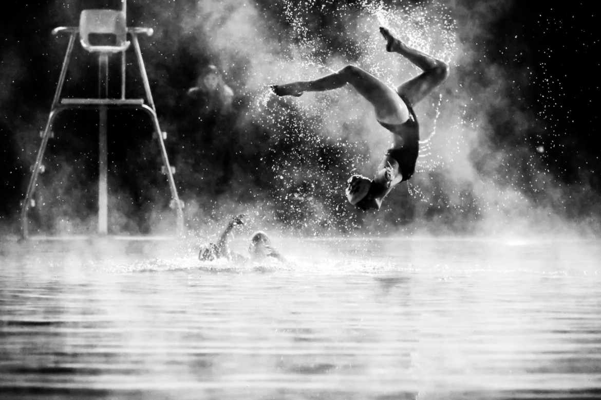 fot. James Rokop, "Synchro Steam", wyróżnienie w kat. Sports in Action / Siena International Photo Awards 2020<br></br><br></br>Pływaczka wykonuje wyskok z wody podczas ćwiczeń pływania synchronicznego w mroźny zimowy wieczór.