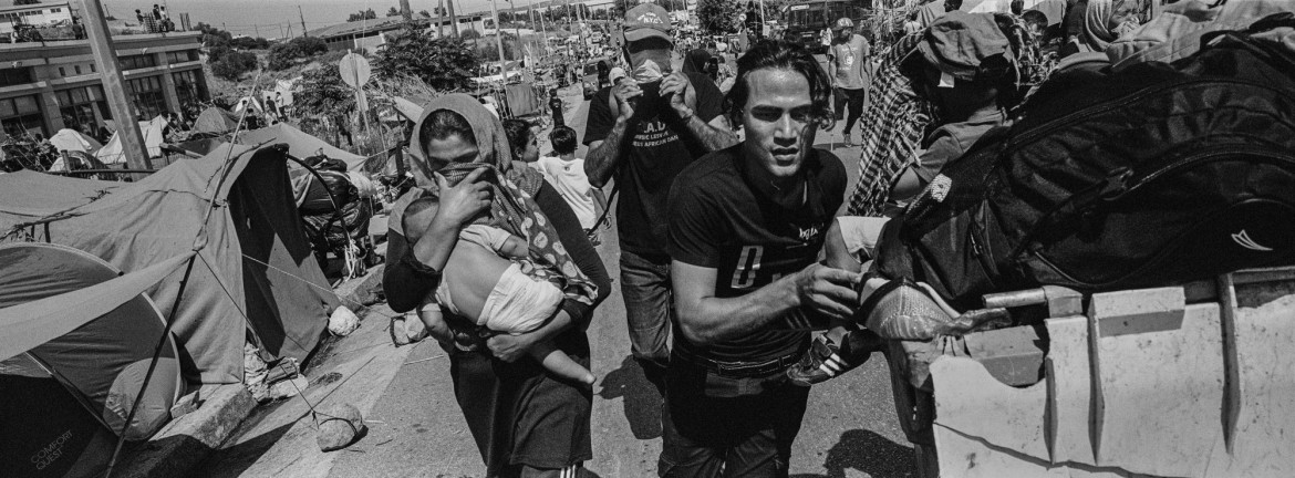 

fot. 
Angelos Tzortzinis, Grecja, z cyklu: "Trapped in Greece", częściowo finansowanego przez Fundację Magnum, nominacja w kategorii "Projekt długoterminowy" / World Press Photo 2021<br></br><br></br>

Dziesiątki tysięcy ludzi uciekających z ogarniętych wojną i biedą ojczyzn utknęło w Grecji od czasu apogeum kryzysu uchodźczego w Europie w 2016 roku. Według raportu UNHCR z marca 2016 roku, ponad milion osób, głównie uchodźców z Syrii, Iraku i Afganistanu, przekroczyło granicę Grecji od początku 2015 roku. Gdy kraje bałkańskie i europejskie na północ od Grecji zaczęły zamykać swoje granice przed napływającymi migrantami, ponad 90 000 osób pozostało uwięzionych w Grecji, w obozach lub na ulicach. Moria Reception and Identification Center na wyspie Lesbos, we wschodniej części Morza Egejskiego, był największym obozem dla uchodźców w Europie, dopóki nie spłonął w pożarze we wrześniu 2020 roku. Do lata 2020 roku około 20 000 osób mieszkało w obozie zbudowanym tak, aby pomieścić 3000 osób. Mieszkańcy skarżyli się na deszcz, zimno, choroby, brak żywności i bezpieczeństwa, niehigieniczne toalety i brak wody. Pożar, który wybuchł 9 września, prawie całkowicie zniszczył obóz. Rząd grecki powiedział, że ogień został wzniecony celowo przez migrantów protestujących przeciwko zamknięciu obozu w związku z epidemią COVID-19. Na pobliskiej wyspie Samos, pod koniec 2019 roku, prawie 8000 uchodźców mieszkało w byłej bazie wojskowej, która została zbudowana, aby pomieścić 650 osób. Mieszkańcy wyspy regularnie organizowali protesty domagając się przeniesienia obiektów na stały ląd, a mieszkańcy obozu protestowali w sprawie warunków życia. W dniu 2 listopada 2020 r. w obozie wybuchł pożar, dwa dni po tym, jak wyspę nawiedziło trzęsienie ziemi o sile 6,7 magnitudy. Od 100 do 150 osób straciło swoje domy. Fotograf od ośmiu lat zajmuje się problematyką migracji. Ten projekt - realizowany na Samos i Lesbos, a także w obozach dla uchodźców w całej Grecji - ma na celu zbadanie ludzkich i społecznych zdolności adaptacyjnych.