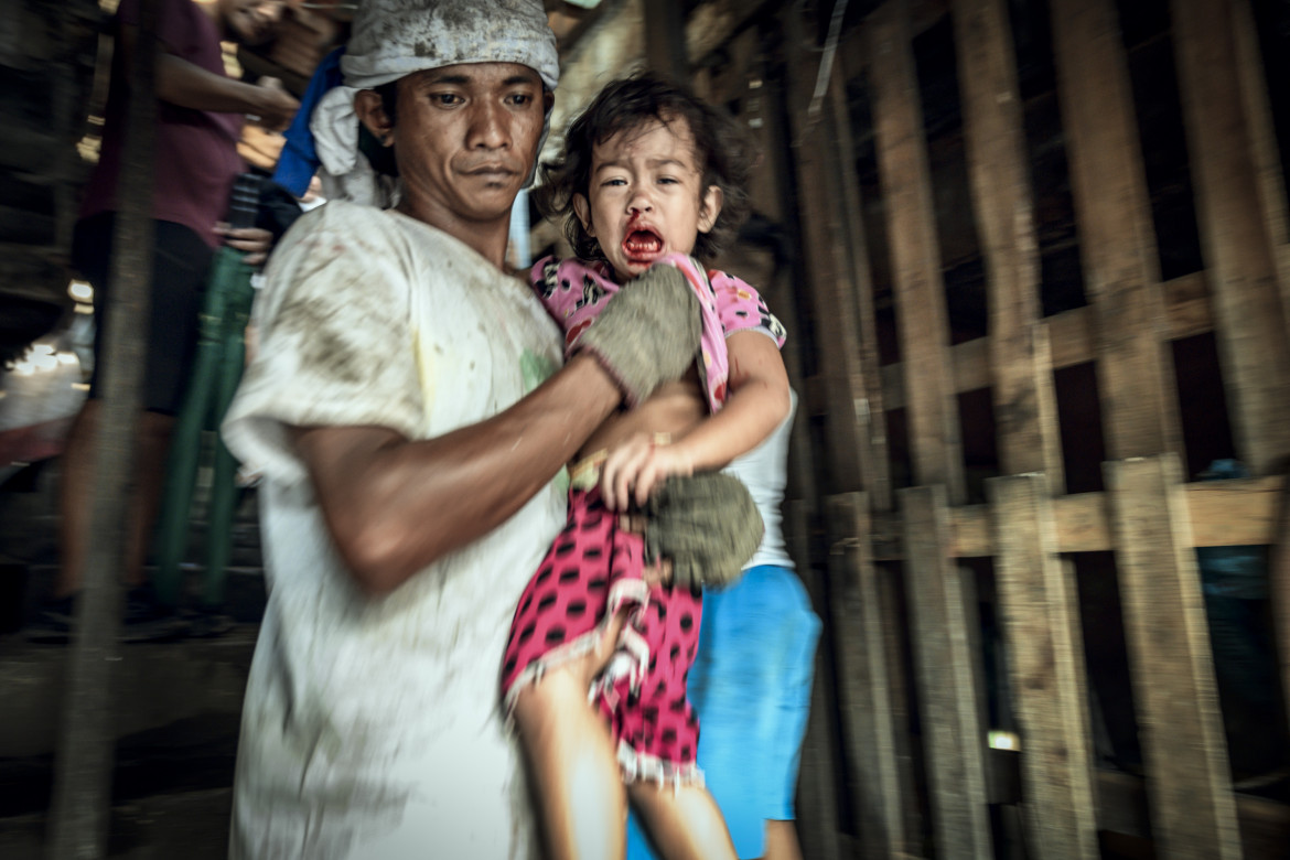 fot. Bernard Kwapiński, "Happyland", Manila, Filipiny<br></br><br></br>W 1995 roku władze Manili zamknęły przepełnione wysypisko śmieci, a pracujących tam ludzi przeniesiono na kawałek ziemi, który był składowiskiem odpadów żywności. Choć pozwolono zostać im jedynie na chwilę, nie opuścili tego miejsca i stworzyli jeden z największych slumsów, dający dzisiaj schronienie ponad 30. tysiącom mieszkańców. HAPPYLAND – ta oficjalna nazwa, powstała ze spontanicznie wymienionych liter w nazwie HAPILAN pochodzącej z lokalnego dialektu Visaian, a która w oryginale określała to miejsce jako ziemię cuchnącą. Historia jest zapisem zjawisk, które uznałem za najbardziej przejmujące, szczególnie tych, związanych z żyjącymi w tym nieszczęściu dziećmi.<br></br><br></br>Bernard Kwapiński – fotograf z wykształcenia i zamiłowania. Absolwent Wydziału Fotografii Uniwersytetu w Dortmundzie (Visual Communication / Photography). Członek Press Club Polska oraz założyciel Fundacji Instytut Fotografii Fort, którą powołał w roku 2016 celem wspierania fotografii polskiej. Założyciel galerii fotograficznej działającej przy IFF, a także jedynej w Polsce, unikatowej czytelni fotograficznej na rzecz, której przekazał jedną z największych w kraju kolekcji książek fotograficznych. Publikował swoje prace w prasie zagranicznej i polskiej ( m.in. w National Geographic Polska) i prezentował swoje zdjęcia na portalach internetowych ( m.in. Lens Culture). Od trzech lat pracuje nad kilkoma długoterminowymi projektami, których celem będą publikacje książkowe.